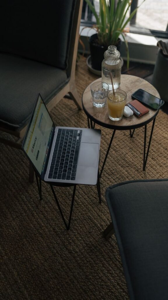 A cozy indoor workspace featuring a laptop, drinks, and smartphone on a table.
