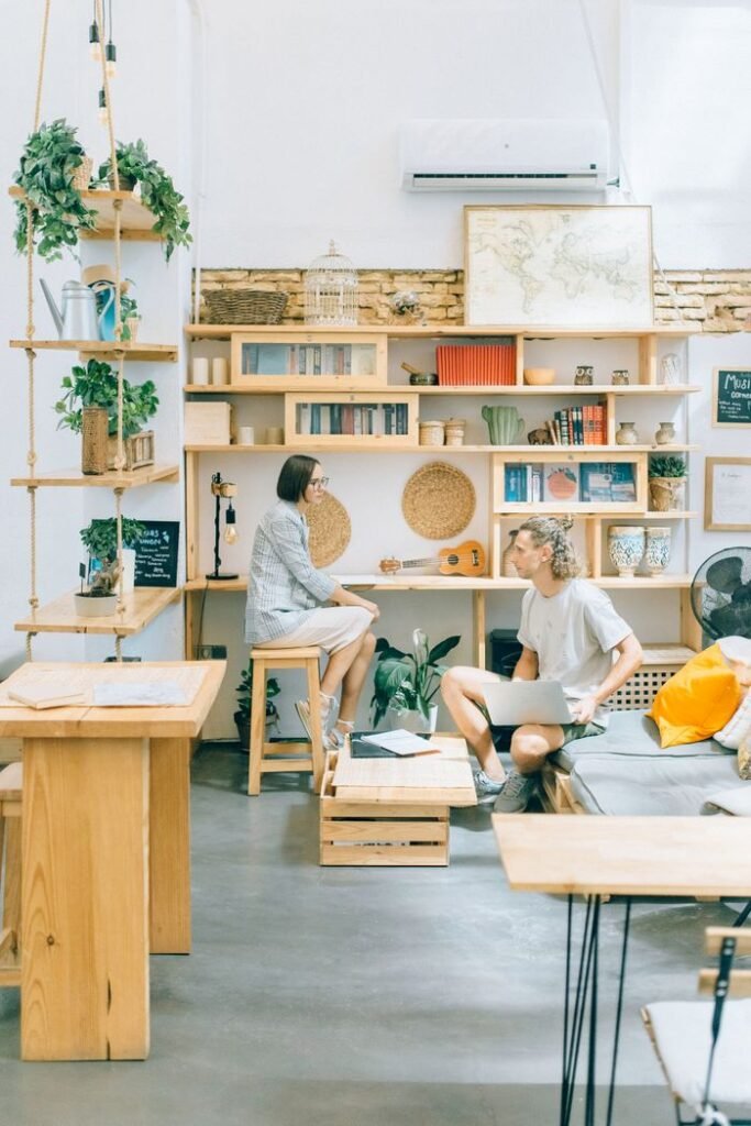 A bright modern workspace featuring two adults interacting in an open-plan office with plants and natural decor.